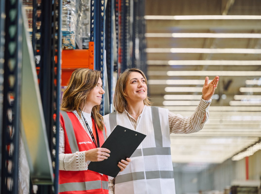 Two logistics specialists in a warehouse discussing logistics solutions for different industry sectors.
